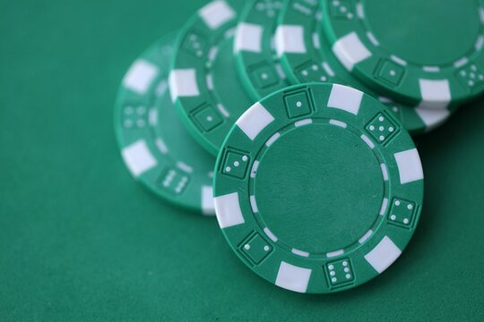 Green casino poker chips on green gaming table close up. Few amount of green casino chips
