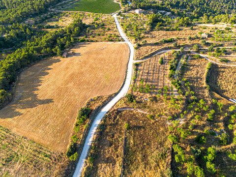 Winding road aerial countryside farmland fields agriculture landscape drone view across Catalonia Spain showing patchwork terrain and rural textures