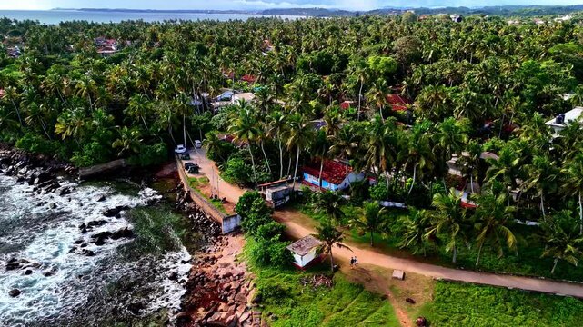 Aerial drone footage of Dondra Head coastline showing a rocky headland, lush greenery and adjacent coastal village.