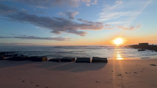 Static beach sunset with concrete coastal blocks in Barbate.