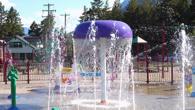 Bright splash pad with water features. Fountains spray water. Playful, refreshing, and vibrant summer scene. Waterton, AB, Canada
