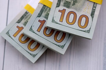 Three packs of ten thousand US dollar bills on wooden background. Packs of hundred dollar bills in stack on white wood planks close up © mehaniq41