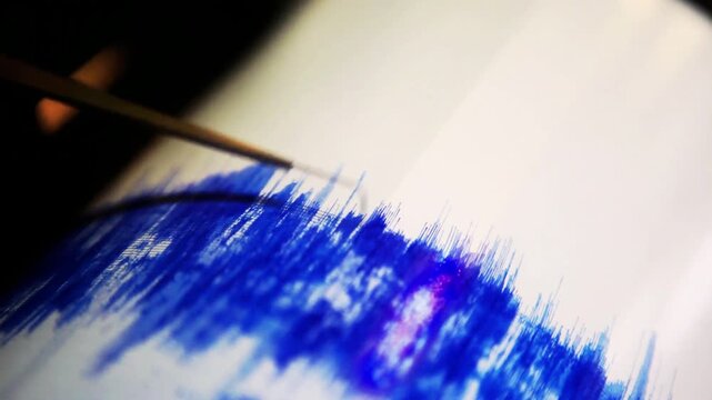 Close view of earthquake seismograph recording wave patterns, needle tracing shaking activity on paper drum, scientific measurement device in lab, dramatic motion, educational documentary style