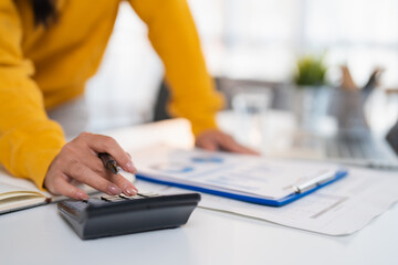 Fototapeta premium Accountant or businesswoman analyzing financial data and statistics, using a calculator to manage expenses, budget, and income statements for a company or personal finances