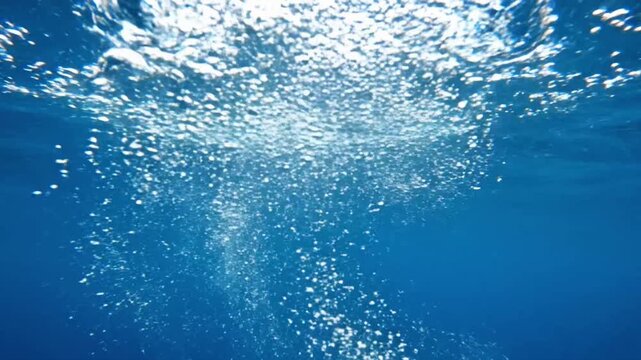 Bubbles rising from underwater in a clear ocean environment during a bright sunny day