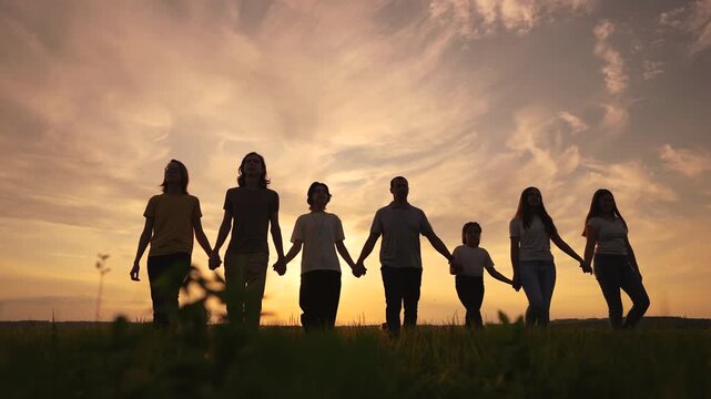 community big family in the park. large group of lifestyle people holding hands walking silhouette nature sunset in the park. big family childhood dream concept. people in the park. big family