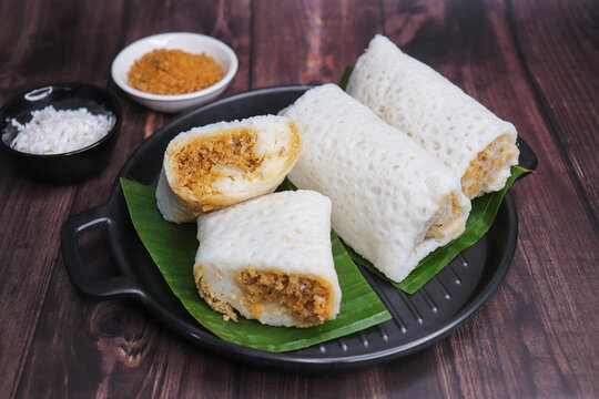A closeup shot of a traditional Goan Alle Belle coconut pancakes. The crepes are rolled neatly and filled with a rich, dark brown mixture of grated coconut and palm jaggery. popular tea time snack.