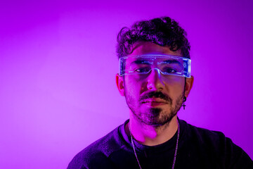 Obraz premium Man wearing augmented reality glasses, looking at viewer in purple neon light