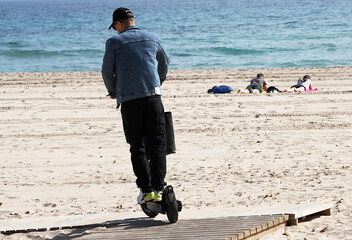 Conductor de patinete el&eacute;ctrico veh&iacute;culo de movilidad personal, playa y mar en verano