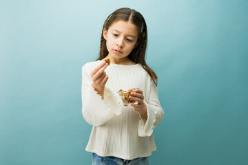 Little girl showing concern while holding a walnut, representing childhood nut allergies and...