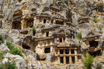 Naklejka premium A horizontal shot showcasing the detailed architectural facades of ancient Lycian tombs carved into the vertical limestone cliffs at Myra in Demre, Turkey.