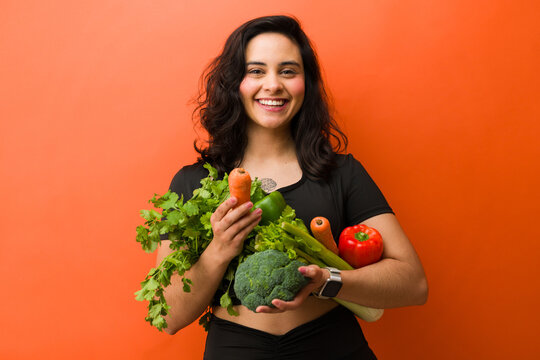 Young woman smiling while holding fresh vegetables, living a healthy lifestyle focusing on nutrition and wellness