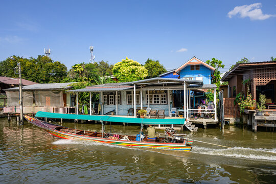 Bangkok, Thailand - A khlong or channel of the Chao Phraya River with colorful longtail wooden boats and traditional residential buildings in Bangkok