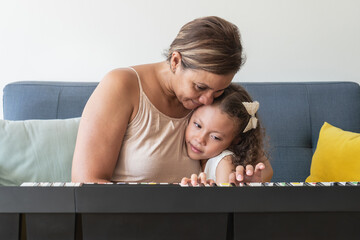 Grandmother teaching grandchild playing piano, music education lesson © Hector Pertuz