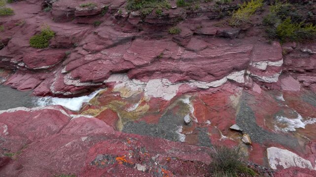 Stream flowing through layered red rock formations in Waterton Lakes National Park