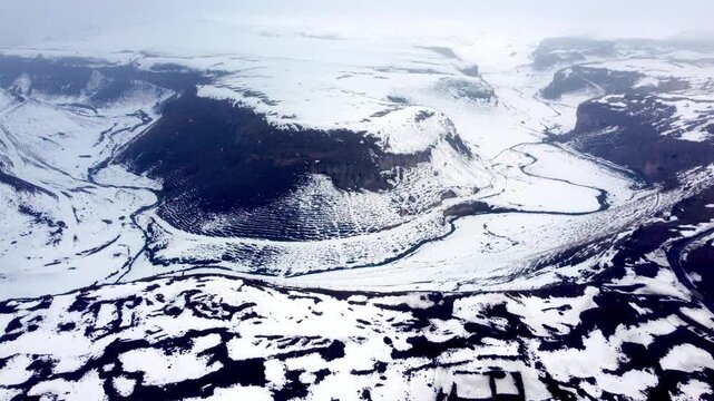 High-altitude drone footage capturing the serpentine river that forms the border between Turkey and Armenia, surrounded by the snowy ruins of Ani