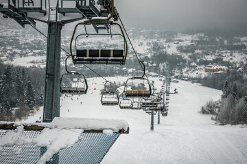 Chair ski lift in snowy cloudy mountain on ski resort