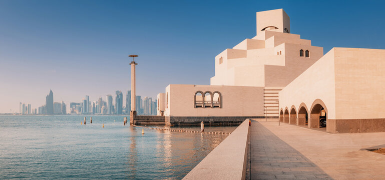 29 November 2025, Doha, Qatar: Museum of Islamic Art standing on the waterfront with a modern cityscape and palm trees in the background