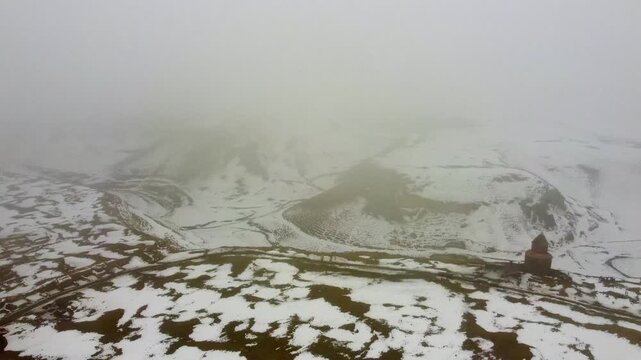 A drone exploration of the steep canyons and rocky cliffs surrounding the medieval city of Ani, showing ancient cave dwellings and structures in the snow