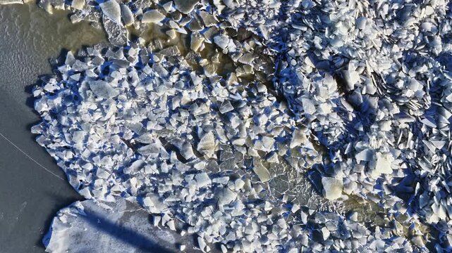 Broken ice sheets on frozen water, creating intricate cold patterns and abstract shapes