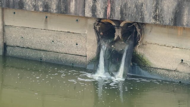 Water flowing from urban stormwater drainage pipes into a concrete canal. City water management infrastructure and environmental engineering system in Southeast Asia.
