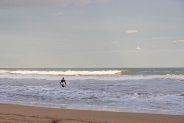 A surfer in the Mediterranean sea, Spain, wades through waves during a calm day.