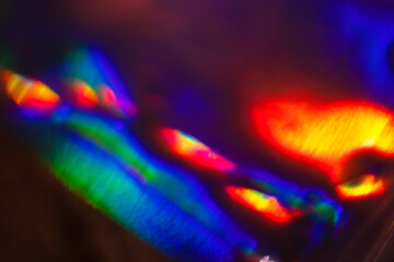 Colorful abstract light patterns created by reflections and refractions on a surface, showcasing vibrant hues of blue, green, red, and yellow in a blurred composition