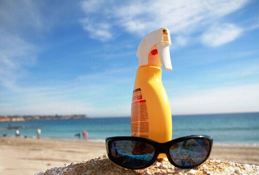 Playa, crema protectora y gafas de sol junto al mar en verano de vacaciones