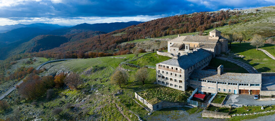Fototapeta premium Aerial drone view of the autumn landscape surrounding the beech forest and the Sanctuary of San Miguel de Excelsis in the Sierra de Aralar. Huarte-Araquil, Navarre, Spain, Europe