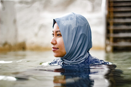 Filipina woman wearing light blue headscarf submerged in a clear tidal pool
