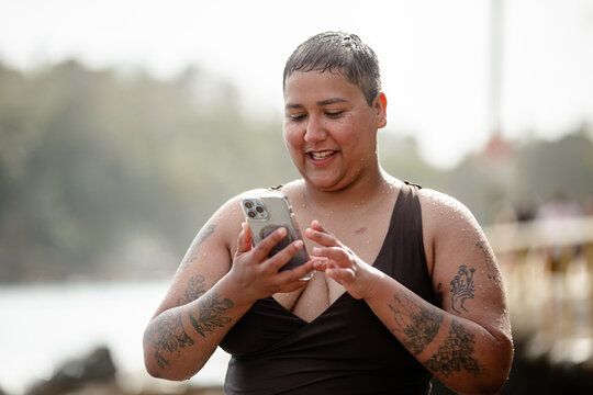 Woman wearing brown swimsuit scrolling her phone
