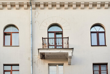 Failing balcony support structure cracked and chipped concrete slab with large areas of peeled plaster exposing masonry under rusty wrought iron railing on aged white building facade, safety hazards © Tricky Shark