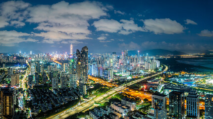 Obraz premium Modern city skyline with illuminated skyscrapers and busy highways at night in Shenzhen, China.