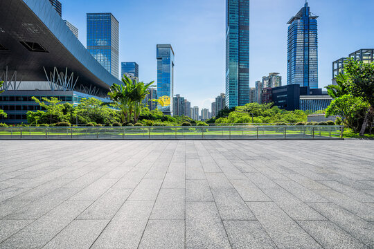 Empty stone plaza in front of modern skyscrapers and green park in Shenzhen, China.