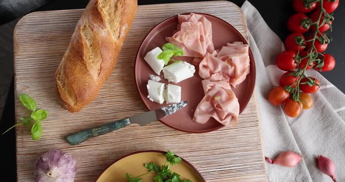 High-quality farm food on wooden cutting board. Top view. Flat lay photo. Soft goat cheese on bread, basil and mortadella sandwich. Italian tradition cuisine.