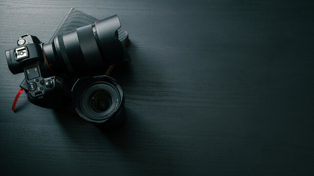 Professional camera and lenses laid out on a dark wooden surface, ready for use