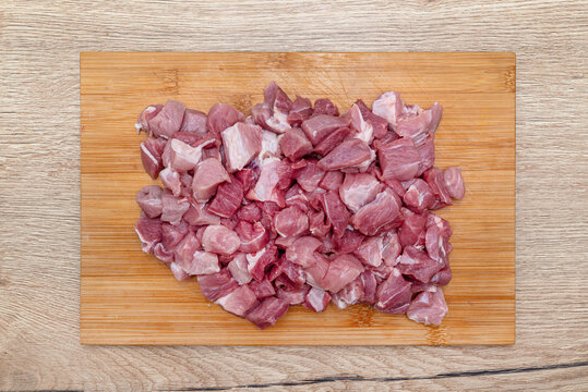 Raw pork shoulder and neck diced on cutting board