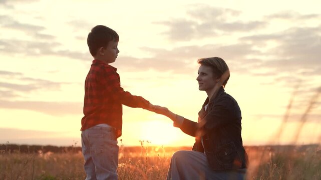 Boy extends hand to mother signifying sense of trust. Boy through connection experiences care with mother. Boy in midst of nature with mother reaches out to sharing profound feeling of freedom