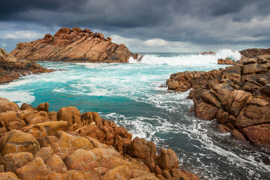 Low angled view of large waves crashing through channels along a rocky coastline