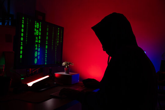 silhouette cyber crime. silhouette Senior man hacker hacking computer. anonymous hacker wearing black hoodie in dark room. online scam and cyber security threat.