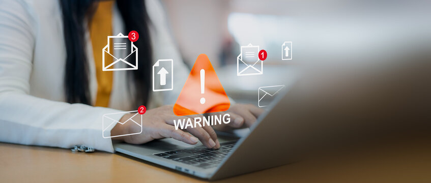 Email phishing warning icon overlay. Cybersecurity alert, Businesswoman using laptop with internet scam and fraud notification concept in modern office workspace.