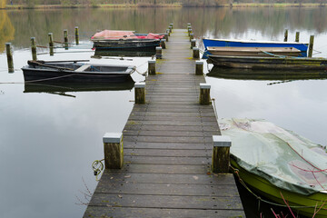 Naklejka premium Wooden pier with moored boats on still lake