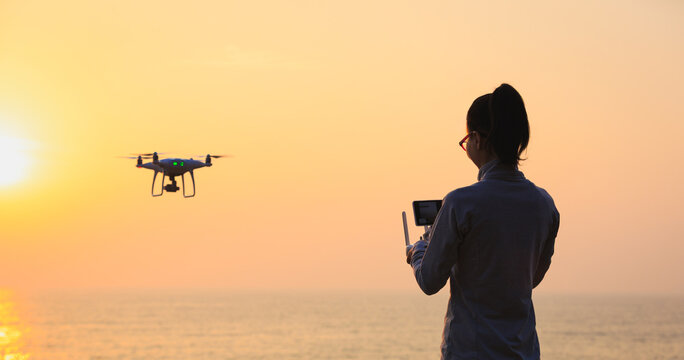 Silhouette of remote control a flying drone which taking photo over sunrise sea