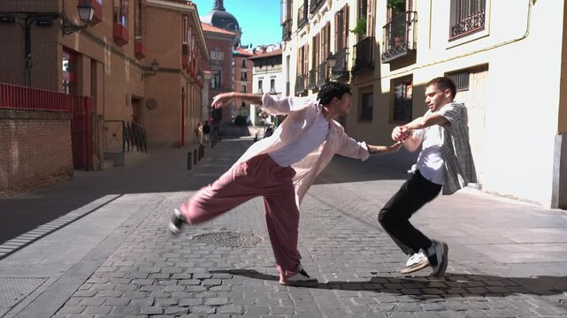 Two young men performing a contemporary street dance routine on a cobblestone street in a european city, showing synchronized and expressive movements