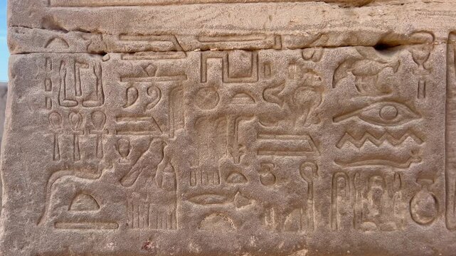 Hieroglyphs carved into stone on one of the walls of the Temple of Hathor in Dendera, Egypt.