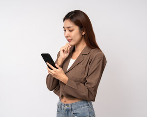 Fototapeta premium Pretty young asian woman using smartphone feeling upset confused bad depressed emotional standing on isolated white background. Holding cell phone. Thinking and stressed