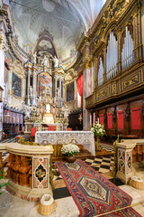 Obraz premium Richly decorated Baroque altar in a church in Clusone, Italy, with marble details, frescoes, organ pipes and floral arrangements. Warm light and solemn sacred atmosphere.