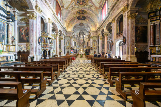 Ornate Baroque church interior in Clusone, Italy, with frescoed ceiling, marble columns and wooden pews, bathed in warm light. Symmetrical and peaceful sacred space.