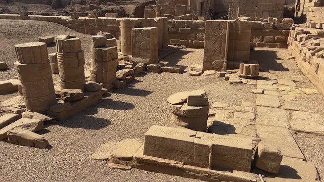 Ruins of the Temple of Hathor complex in Dendera, Egypt, featuring ancient stone structures and remnants of sacred architecture set against a desert landscape.