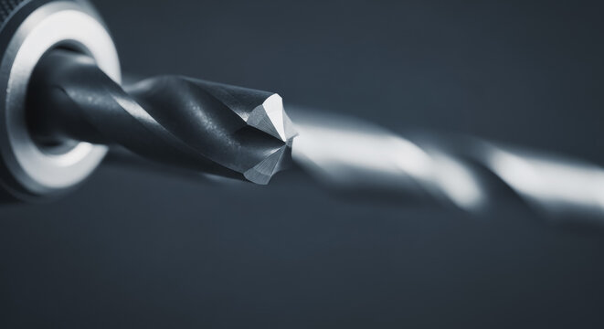 Close-up of a sharp metal drill bit rotating in a drill chuck, highlighting the precision engineering of this essential power tool accessory for drilling tasks.
